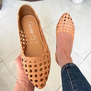 K&ouml;nnte beinhalten: Ein Paar beigefarbene geflochtene Lederschuhe mit spitzer Zehenkappe. Die Schuhe haben ein Kreuzmuster und sind von der Marke "Crucos".