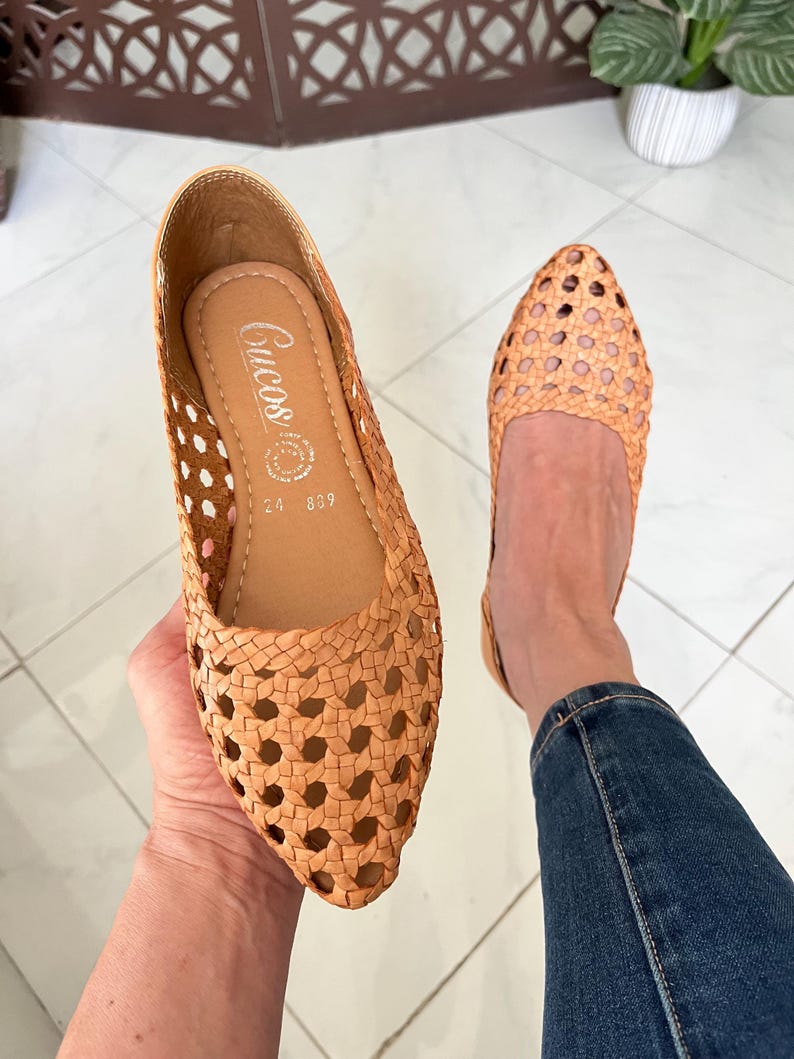 K&ouml;nnte beinhalten: Ein Paar beigefarbene geflochtene Lederschuhe mit spitzer Zehenkappe. Die Schuhe haben ein Kreuzmuster und sind von der Marke "Crucos".
