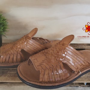 Könnte beinhalten: Ein Paar braune Ledersandalen mit geflochtenen Riemen. Die Sandalen haben eine schwarze Gummisohle und sind in Mexiko hergestellt.