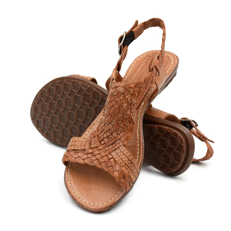 May include: A pair of brown leather sandals with woven straps and a buckle fastening. The sandals have a comfortable, cushioned footbed and a sturdy sole.