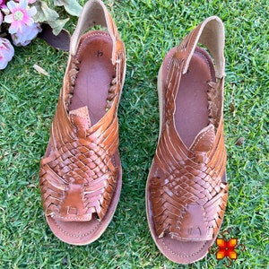 May include: A pair of brown leather sandals with woven straps. The sandals have a simple design and are made of high-quality leather.