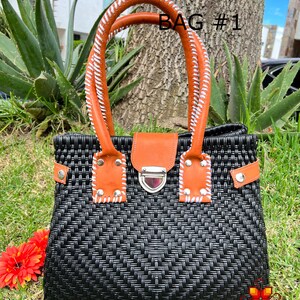 May include: Black woven handbag with brown leather handles and a silver clasp. The bag has white stitching on the handles and a woven pattern on the front. The text "BAG #1" is visible in the image.