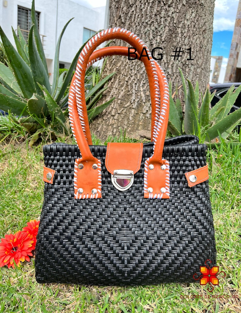 May include: Black woven handbag with brown leather handles and a silver clasp. The bag has white stitching on the handles and a woven pattern on the front. The text "BAG #1" is visible in the image.