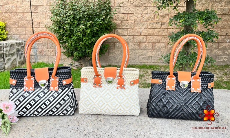 May include: Three woven tote bags with orange leather handles and a silver clasp. The bags are black and white, natural, and black.
