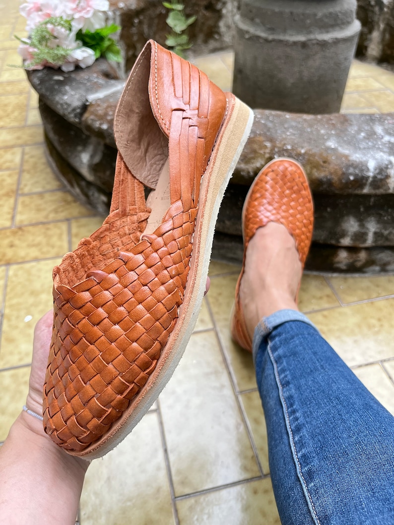 Pu&ograve; includere: Un paio di sandali in pelle marrone con un design intrecciato. I sandali hanno una suola piatta e sono realizzati in pelle morbida e flessibile.