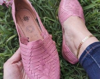 May include: Pink leather sandals with a woven design. The sandals have a strap across the top of the foot and an ankle strap. The sandals are made in Mexico.