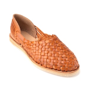 Pu&ograve; includere: Un paio di sandali in pelle intrecciata di colore marrone chiaro. I sandali hanno una tomaia intrecciata e una suola piatta.