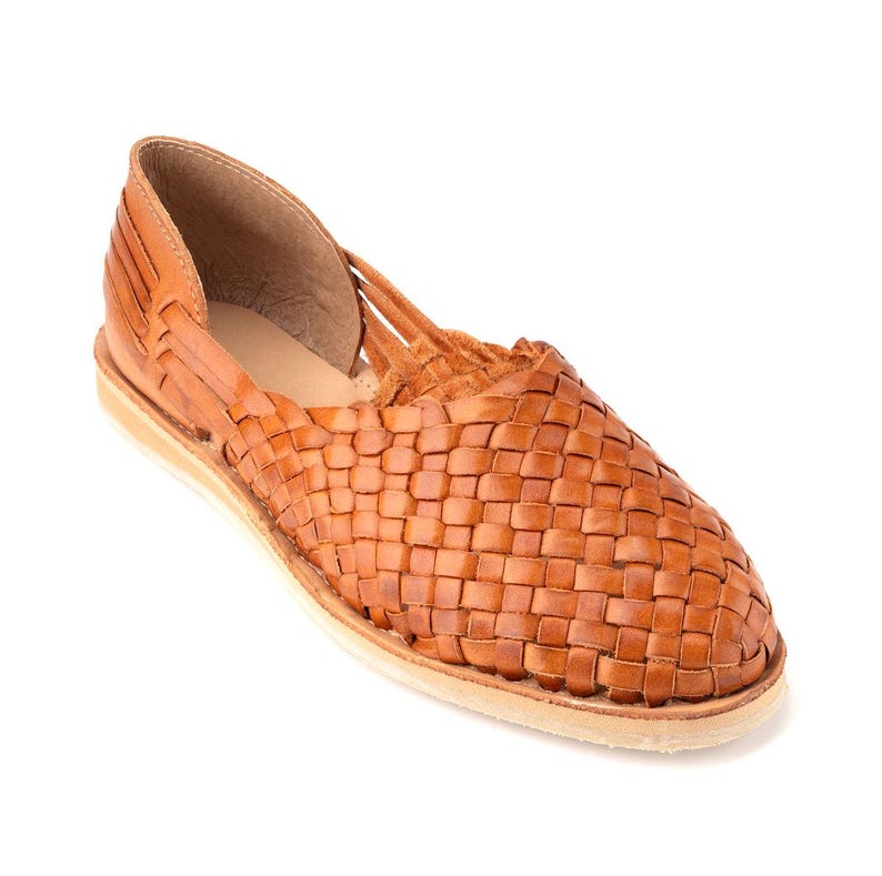 Pu&ograve; includere: Un paio di sandali in pelle intrecciata di colore marrone chiaro. I sandali hanno una tomaia intrecciata e una suola piatta.