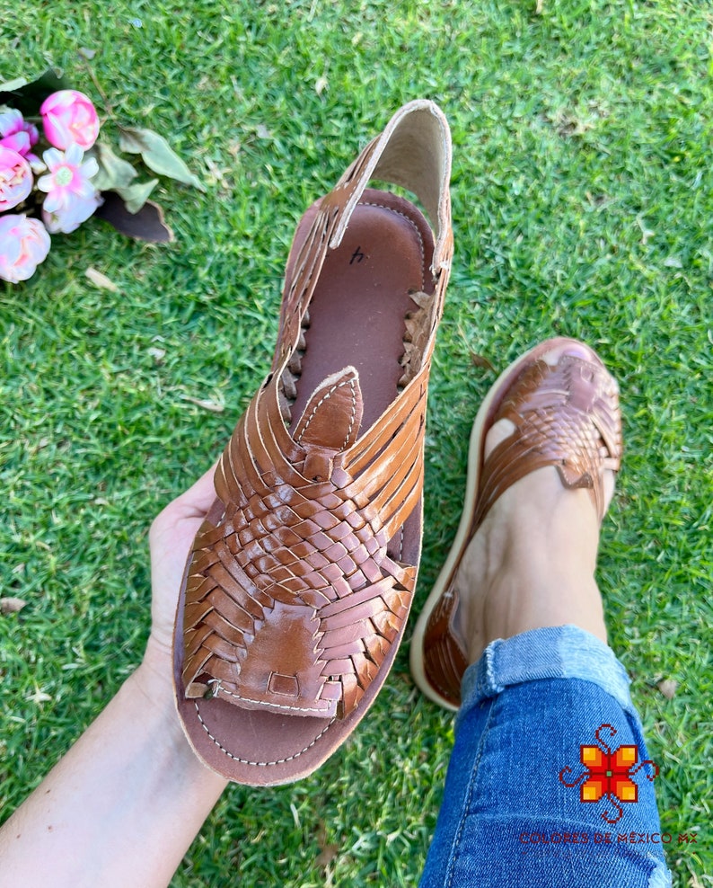 May include: Brown leather sandals with a woven design. The sandals have an open toe and a strap that goes around the ankle.