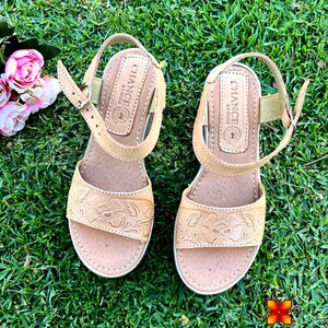 Peut inclure: Une paire de sandales en cuir tann&eacute; avec des broderies florales. Les sandales ont une fermeture &agrave; boucle et une semelle compens&eacute;e. Le nom de la marque "Chance" est imprim&eacute; au dos de chaque sandale.