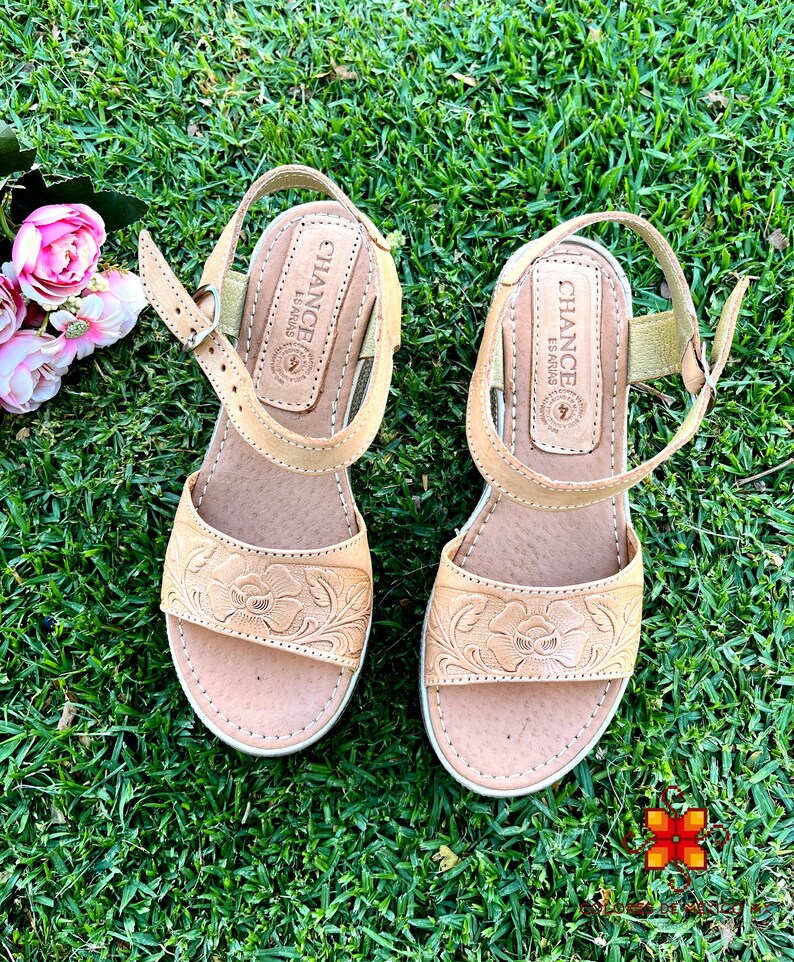 Peut inclure: Une paire de sandales en cuir tann&eacute; avec des broderies florales. Les sandales ont une fermeture &agrave; boucle et une semelle compens&eacute;e. Le nom de la marque "Chance" est imprim&eacute; au dos de chaque sandale.