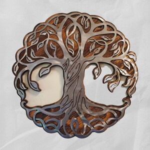 K&ouml;nnte beinhalten: Runde Wanddekoration mit einem Lebensbaum-Motiv. Der Baum ist aus silberfarbenem Metall gefertigt und vor einem Holzgrund platziert. Das Design umfasst detaillierte &Auml;ste, Bl&auml;tter und Wurzeln, wodurch ein symboltr&auml;chtiges Dekor entsteht.