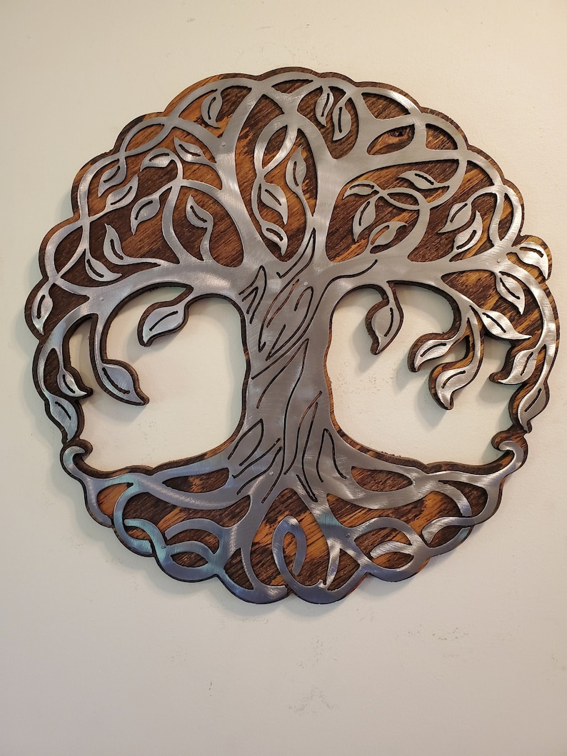 K&ouml;nnte beinhalten: Runde Wanddekoration mit einem Lebensbaum-Design. Der Baum ist aus silberfarbenem Metall gefertigt und vor einem Hintergrund aus gebeiztem Holz platziert. Die &Auml;ste und Bl&auml;tter des Baumes sind in einem kreisf&ouml;rmigen Rahmen enthalten.