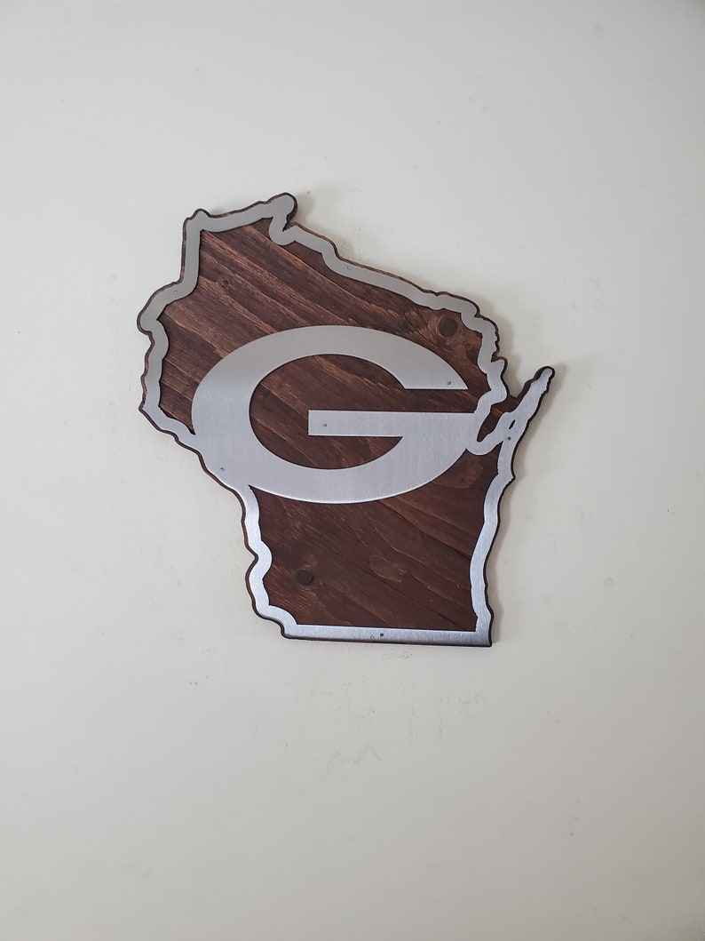 Close angled view of the curved wall decor with a steel emblem layered over dark brown stained wood and a silver border along the edge.