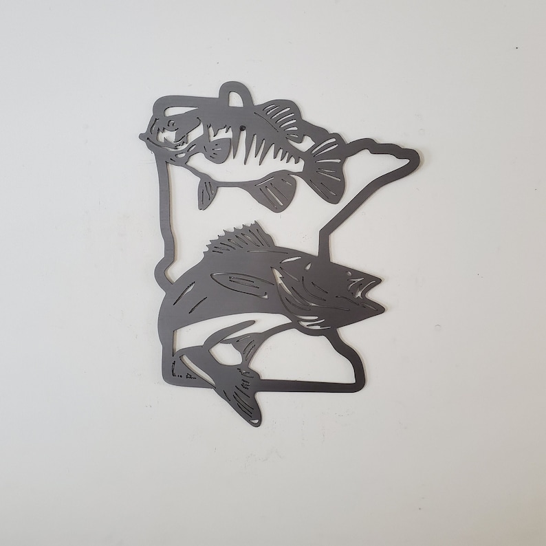 K&ouml;nnte beinhalten: Metallausschnitt des Bundesstaates Minnesota mit zwei Fischsilhouetten. Der gr&ouml;&szlig;ere Fisch ist ein Zander und der kleinere ein Barsch.