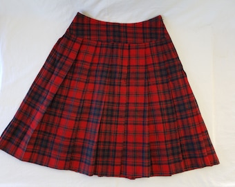 May include: A red and black plaid skirt with a pleated design. The skirt has a classic tartan pattern, with a red base and black intersecting lines. The skirt is made of a woven fabric and has a zipper closure.