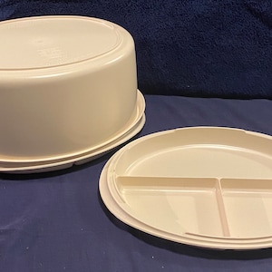 May include: A beige plastic cake carrier with a lid and a removable, divided serving plate.
