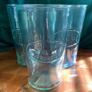 May include: Three clear glass juice glasses with a green tint. The glasses have a raised embossed design that says "Jus de Fruits".