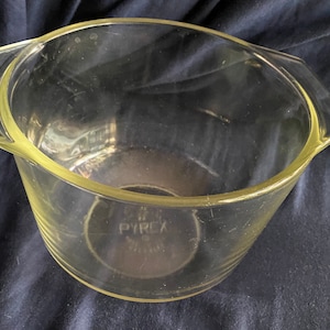 May include: A clear glass mixing bowl with two handles. The bowl has the word "PYREX" printed on the bottom.