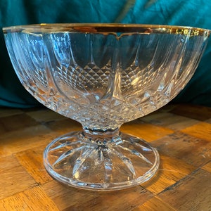 May include: A clear glass bowl with a gold rim and a diamond pattern. The bowl sits on a pedestal base.