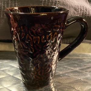 May include: A black ceramic coffee mug with a textured surface and the word "Jamaica" embossed on the side.