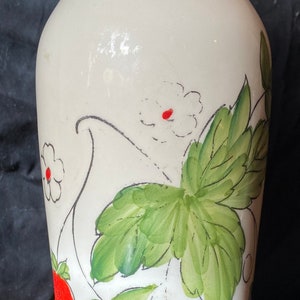 May include: White ceramic vase with a green rim and hand-painted strawberries, leaves, and flowers.