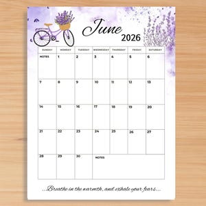 Puede incluir: Una página de calendario mensual de junio de 2026 con un fondo de acuarela morado, ramas de lavanda y una ilustración de una bicicleta con una cesta de flores. La cuadrícula incluye los días de la semana, fechas y el texto, Breathe in the warmth, and exhale your fears.