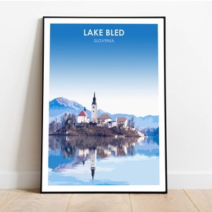 May include: A scenic poster featuring a picturesque view of Lake Bled in Slovenia. The image showcases a small island with a church and a bell tower, surrounded by clear blue water and snow-capped mountains in the background.