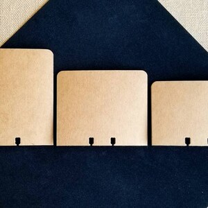May include: Three brown paper envelopes with three holes punched in the bottom edge. The envelopes are different sizes and are arranged from largest to smallest.