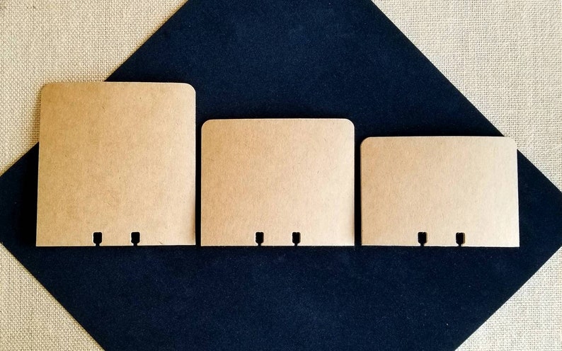 May include: Three brown paper envelopes with three holes punched in the bottom edge. The envelopes are different sizes and are arranged from largest to smallest.