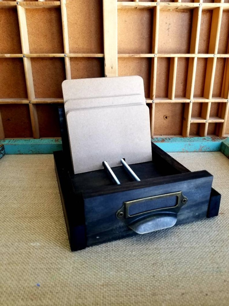 May include: A dark wooden drawer with a metal handle and a label. The drawer is open and contains several pieces of cardboard.
