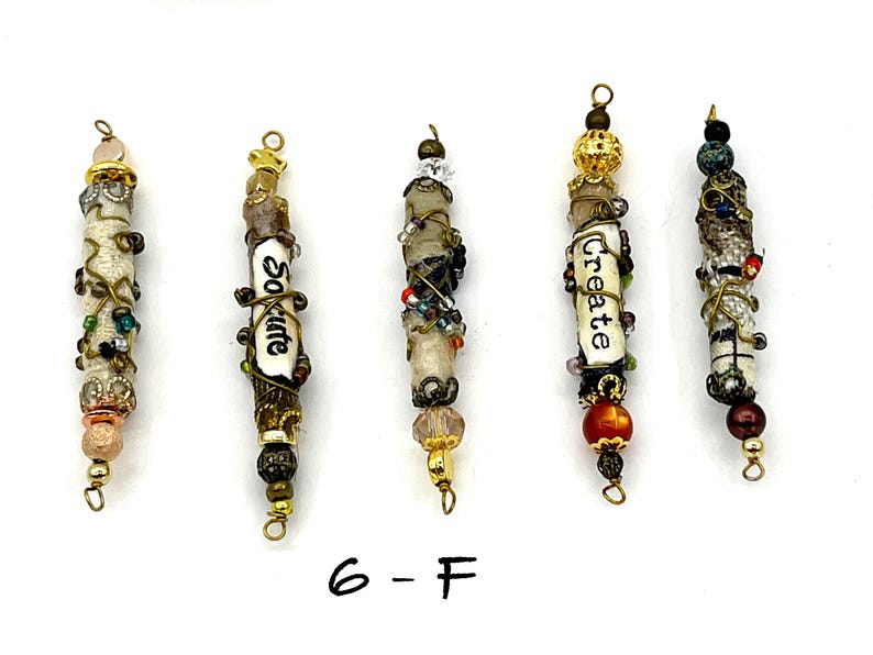 May include: Five beaded charms with different words and designs. The charms are made of white beads, brown beads, gold beads, and other colorful beads. The words on the charms are "So cute", "Create", and "Love".