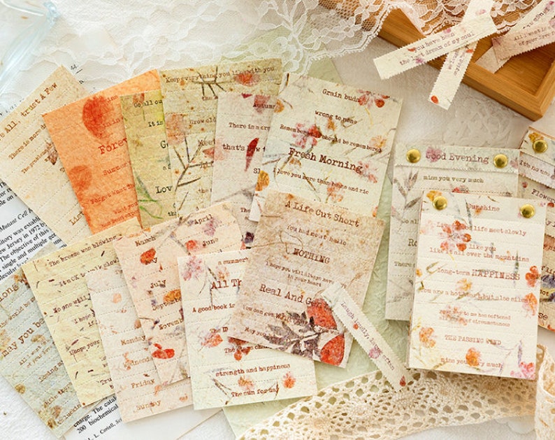 Puede incluir: Una colecci&oacute;n de ef&iacute;meras de papel de estilo vintage con flores prensadas y citas inspiradoras. El papel es beige y crema con acentos marrones y rojos. Las citas incluyen "A Life Cut Short", "Fresh Morning", "Good Evening", y "All The", entre otras.