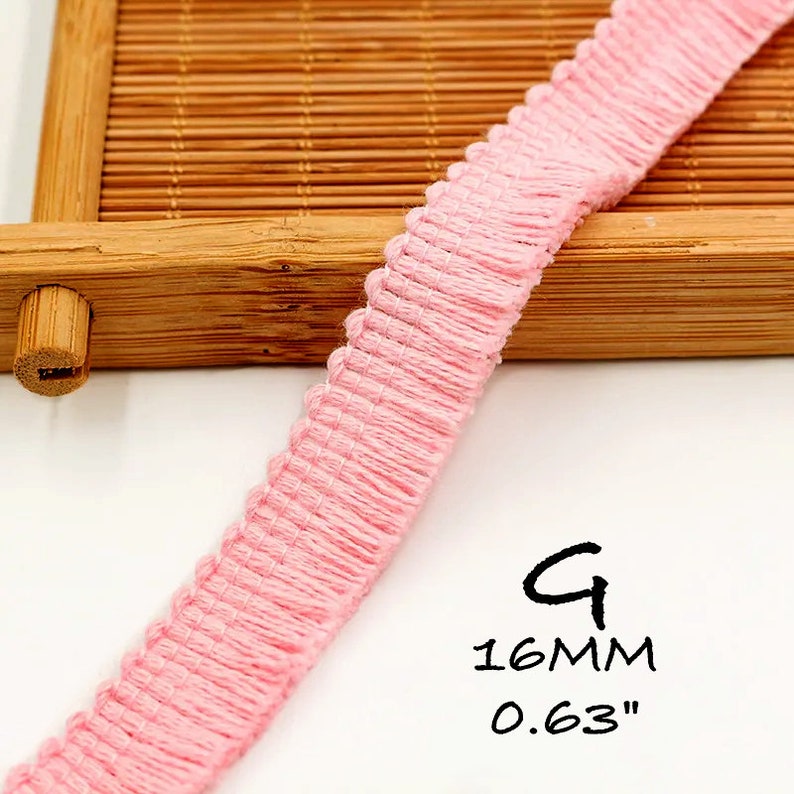 K&ouml;nnte beinhalten: Rosa Baumwollborte mit gekr&auml;useltem Rand. Die Borde ist 1,6 cm breit.