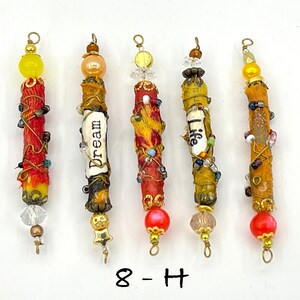 May include: Five colorful, beaded, and wrapped sticks with gold accents and a variety of beads and charms. The sticks are decorated with words like "Dream" and "Life".