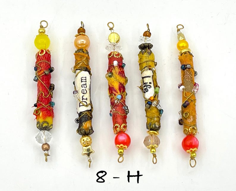 May include: Five colorful, beaded, and wrapped sticks with gold accents and a variety of beads and charms. The sticks are decorated with words like "Dream" and "Life".