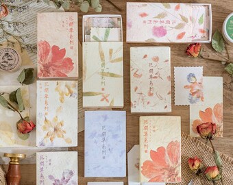 Puede incluir: Surtido de pequeñas cajas con diseños florales y el texto "花間草系列" (hua jian cao xi lie) en caracteres chinos. Las cajas contienen papel decorativo con motivos florales.