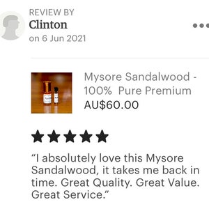 Op de afbeelding: Twee kleine flesjes Mysore-sandelhout etherische olie, een 100% puur premium product, voor AU$60,00. De flesjes zijn van amberkleurig glas met gouden dopjes en etiketten. Het product is met vijf sterren beoordeeld.