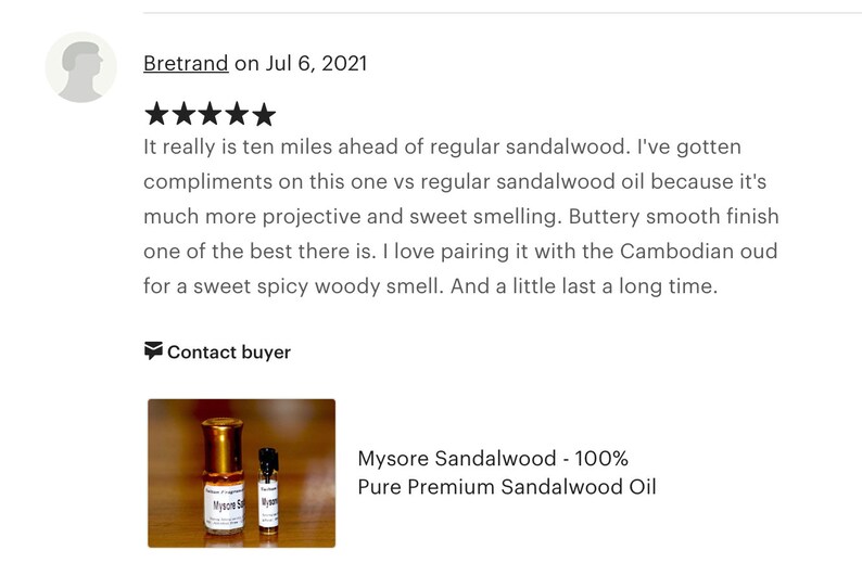 Op de afbeelding: Twee kleine flesjes Mysore Sandelhout 100% Pure Premium Sandelhout Olie. De flesjes zijn van helder glas met gouden dopjes en etiketten. De flesjes staan op een houten oppervlak.