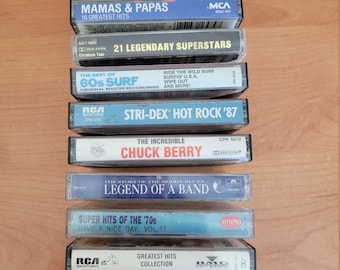 May include: A stack of ten cassette tapes with various artists and album titles. The tapes are all in a standard cassette size and have a variety of colors and designs. The top tape is a black cassette with white text that reads "The Jimi Hendrix Experience/Otis Redding". The bottom tape is a black cassette with white text that reads "Def Leppard Retro Active".