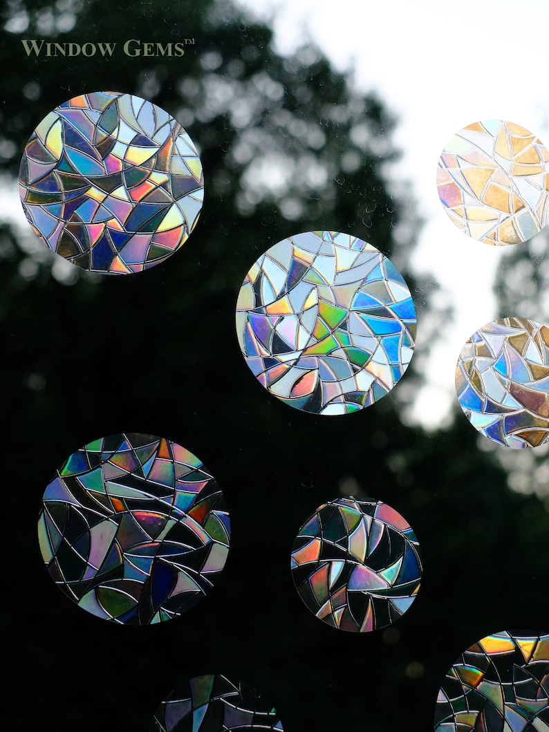 May include: A set of six iridescent window clings in a stained glass pattern. The clings are round and feature a variety of colors, including blue, green, purple, and gold. The clings are designed to add a decorative touch to any window.