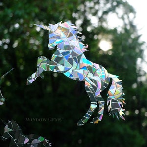 May include: A set of three iridescent unicorn window clings. The unicorns are made of a mosaic-like material that reflects light. The clings are perfect for adding a touch of whimsy to any window.