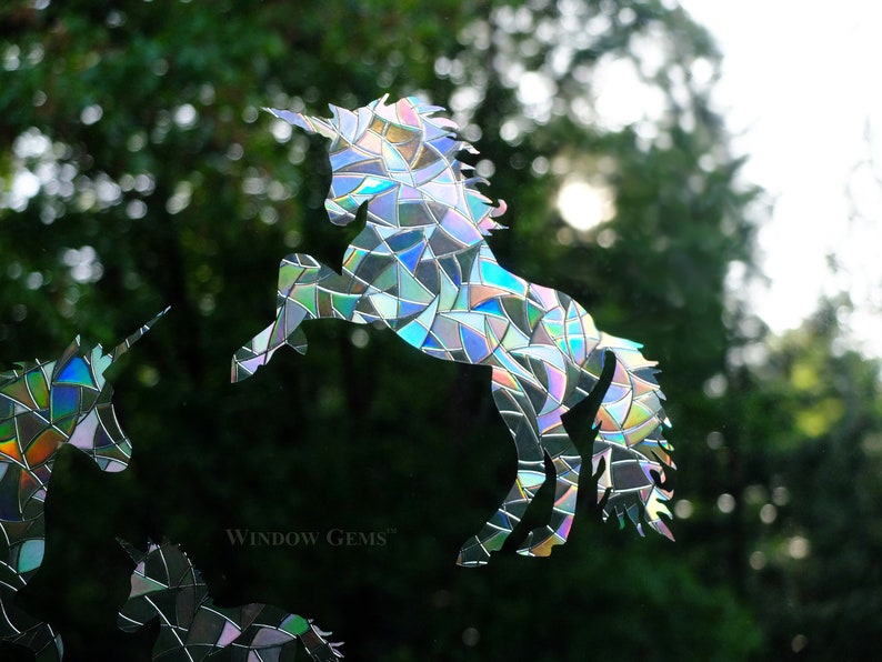 May include: A set of three iridescent unicorn window clings. The unicorns are made of a mosaic-like material that reflects light. The clings are perfect for adding a touch of whimsy to any window.