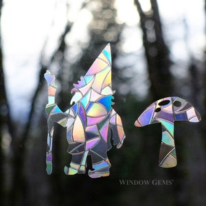 May include: A colorful iridescent gnome and mushroom window cling set. The gnome is holding a staff and has a pointed hat. The mushroom has a rounded top and a stem. The set is made of a clear, iridescent material that reflects light.
