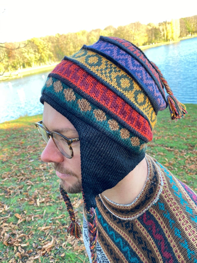Side profile of a model wearing the earflap hat outdoors, showing the vibrant pattern and braided tassel.