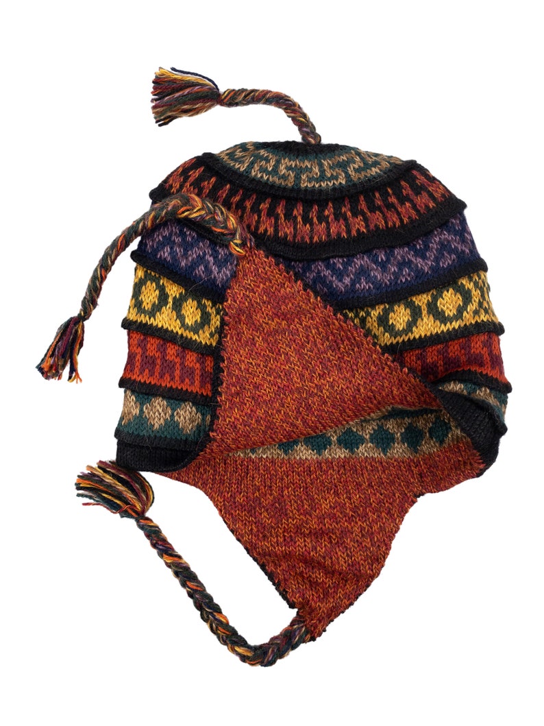 The alpaca wool earflap hat laid flat, displaying its colorful design and tassel details.
