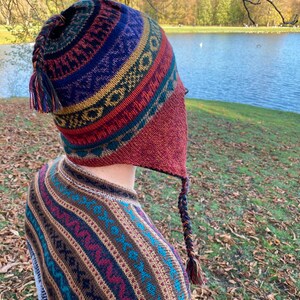 Side view of the model outdoors, with the earflap hat showing the bold color combination and pattern.