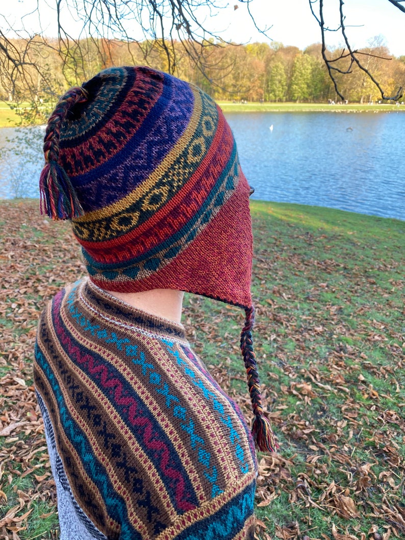 Side view of the model outdoors, with the earflap hat showing the bold color combination and pattern.