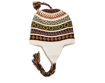 Può includere: Un cappello di lana bianco con un motivo geometrico colorato e le alette per le orecchie. Il cappello ha un lungo pon pon.