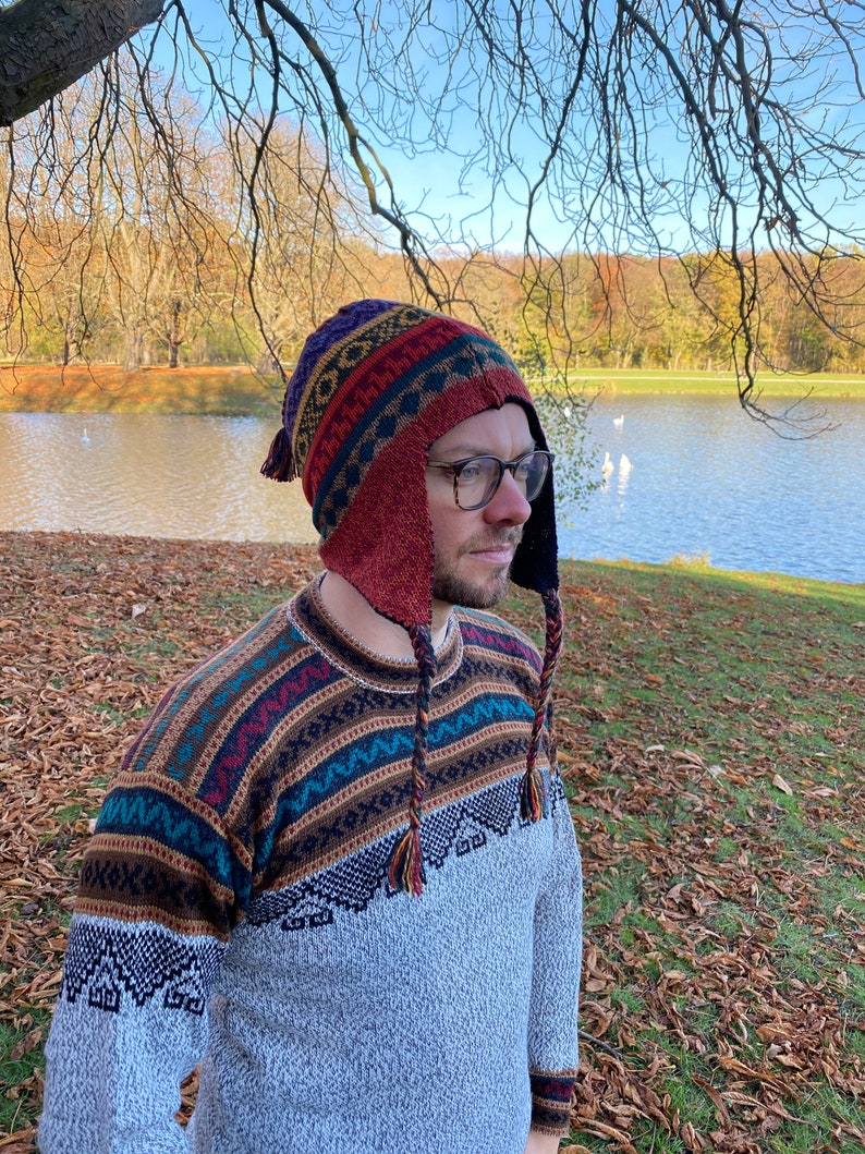 Another side view of the model with the hat, highlighting the pattern, earflaps, and braided tassels near a lake.